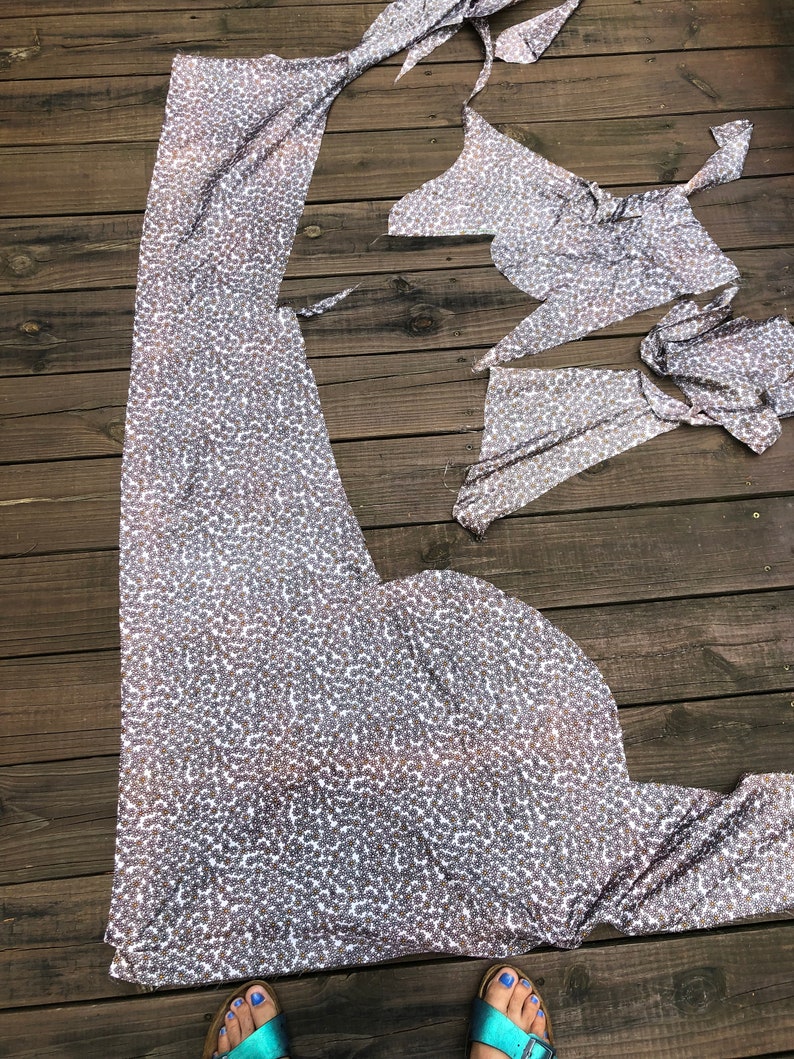 Puede incluir: Piezas de tela con un estampado de lunares plateados y blancos est&aacute;n dispuestas sobre una terraza de madera. La tela parece estar cortada en varias formas, posiblemente para coser una prenda. La imagen est&aacute; tomada desde arriba.