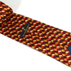 May include: A red, orange, and gold patterned silk tie with a navy blue lining. The tie has a label that reads "Ermenegildo Zegna".