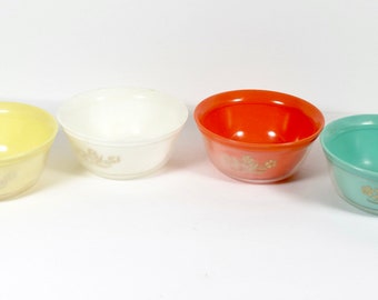 May include: Four mixing bowls in different colors: yellow, white, orange, and green. Each bowl has a floral design in gold.