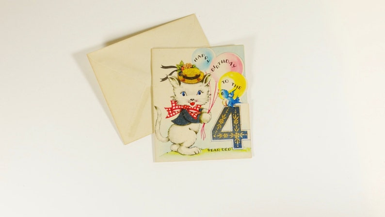 May include: A birthday card featuring a white cat wearing a hat and a red bow tie. The cat is holding a blue bird with a yellow balloon that says "Happy Birthday to the 4 Year Old".