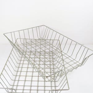 May include: Two silver metal wire mesh trays stacked on top of each other. The trays are empty and have a rectangular shape.