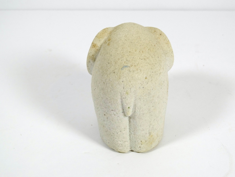 Peut inclure: Une petite figurine d'&eacute;l&eacute;phant en pierre blanche. L'&eacute;l&eacute;phant est tourn&eacute; dos &agrave; la cam&eacute;ra et a une surface textur&eacute;e.