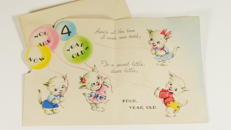 May include: A birthday card with a pop-up design featuring three white kittens holding balloons. The balloons have the words "You are now" and "4 years old" printed on them. The card also has the text "Here's all the love a wish can hold, To a sweet little, dear little, FOUR YEAR OLD."