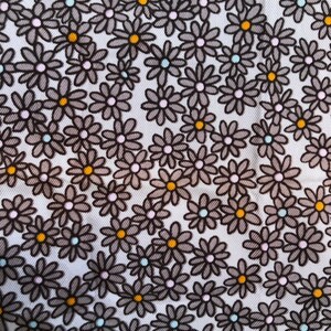Puede incluir: Primer plano de una tela con un estampado floral repetido. Las flores son grises con contornos negros y tienen centros amarillos, rosas y celeste. El fondo es blanco.