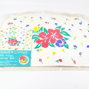May include: A set of 8 vinyl placemats with a tropical flower design. The placemats are white with red, pink, blue, green, and yellow flowers. The set includes 4 placemats and 4 coasters. The packaging says "Summer Living 8 Pc. Vinyl Placemat Set".