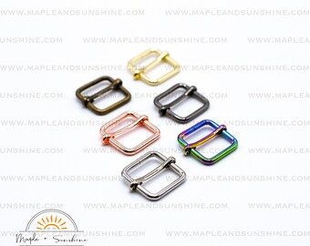May include: Five different colored metal slider buckles. The buckles are square shaped with a rounded corner and have a shiny finish. The colors are gold, silver, black, rose gold, and rainbow.