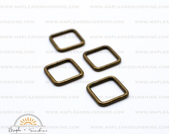 May include: Four antique gold-toned metal square rings. The rings are approximately 1 inch in diameter.