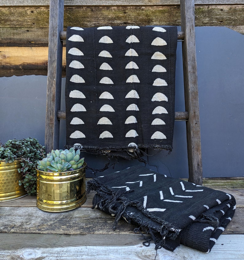 Authentic black dyed african mud cloth with white half circles printed in vertical rows.