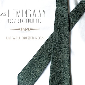 Könnte beinhalten: Eine dunkelgrüne gemusterte Krawatte mit dem aufgedruckten Text "the HEMINGWAY 1937 SIX-FOLD TIE THE WELL DRESSED NECK".