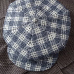 May include: A blue and white plaid newsboy cap with a rounded crown and a flat brim.