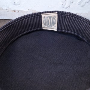 May include: The inside of a black and white striped hat with a white label that says "HDM" in a circle.
