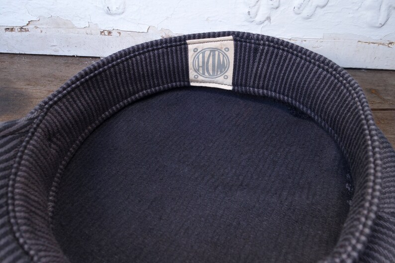 May include: The inside of a black and white striped hat with a white label that says "HDM" in a circle.