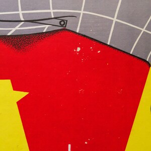 May include: A red and yellow poster with the word "la" printed in white. The poster has a gray and white grid pattern in the upper left corner.