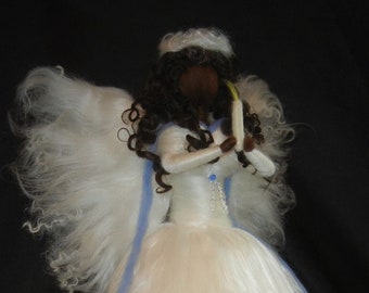May include: A white felt angel doll with a blue ribbon and long flowing hair. The angel is holding a white candle in its hands.