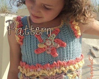 May include: A crocheted girls' top with a scalloped hem and a flower design. The top is in shades of blue, pink, and yellow. The top is worn by a young girl with curly hair and a crocheted flower hair clip.