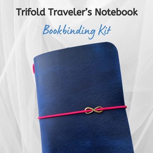 Op de afbeelding: Een marineblauwe Trifold Traveler's Notebook Bookbinding Kit. Het notitieboek is vastgezet met een felroze elastiek en een goudkleurige infinity-bedel. De tekst "Trifold Traveler's Notebook Bookbinding Kit" wordt bovenaan de afbeelding weergegeven.