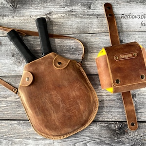 Puede incluir: Una bolsa de cuero marr&oacute;n para raquetas de paddle con dos raquetas y un soporte extra&iacute;ble para cuatro pelotas. El soporte tiene el nombre "Aragon" grabado en relieve.