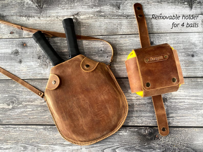 Puede incluir: Una bolsa de cuero marr&oacute;n para raquetas de paddle con dos raquetas y un soporte extra&iacute;ble para cuatro pelotas. El soporte tiene el nombre "Aragon" grabado en relieve.