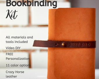 May include: A tan leather journal with a dark brown leather strap closure secured by a brass stud. The strap is embossed with the text BEST DAD. The image includes the text Bookbinding Kit, All materials and tools included, Video DIY, FREE Personalization, 11 color options, and Crazy Horse leather.