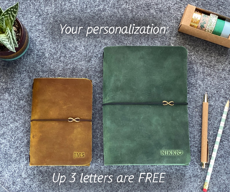 May include: Two leather journals, one brown and one green, with gold infinity symbol accents. The brown journal has the initials "JMS" and the green journal has the name "NIKKI" with a heart symbol. The text "Your personalization" and "Up 3 letters are FREE" are also visible.