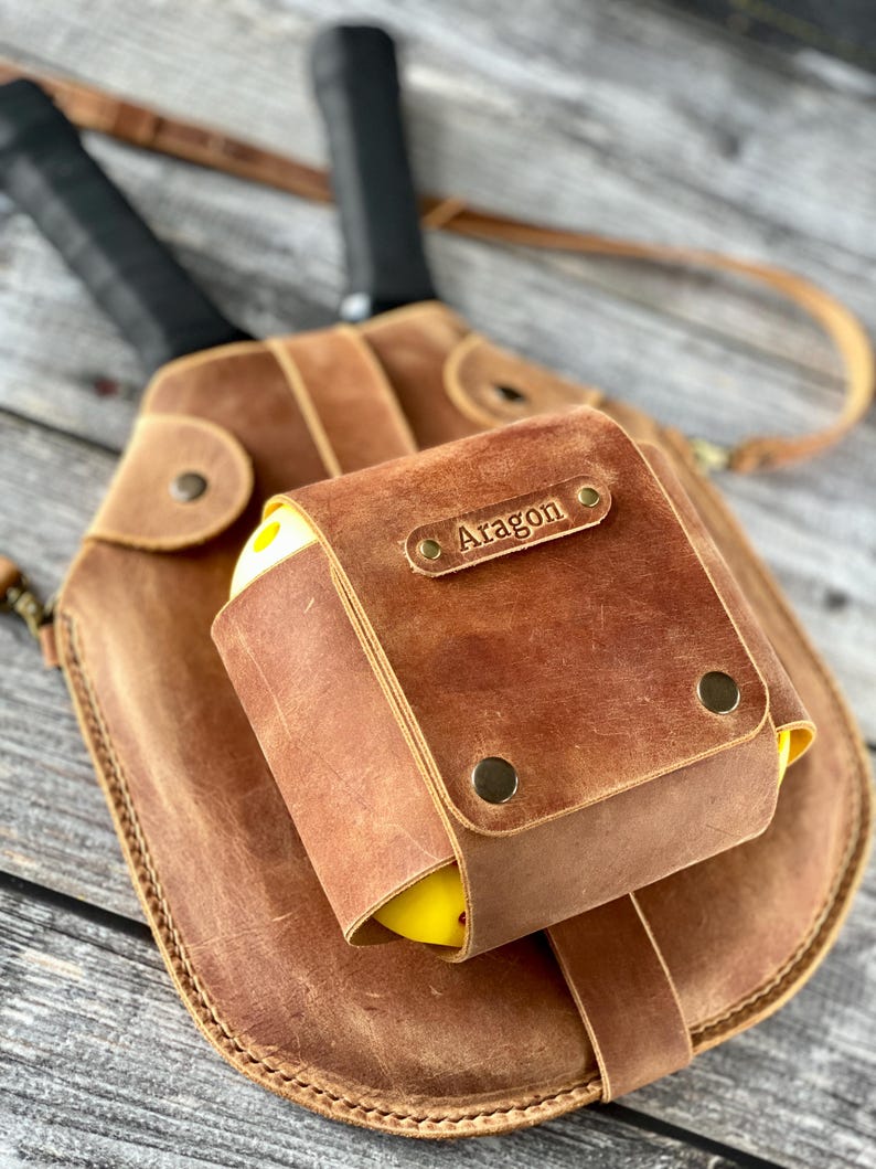 Puede incluir: Un cintur&oacute;n de herramientas de cuero marr&oacute;n con una peque&ntilde;a bolsa que tiene el nombre "Aragon" grabado en &eacute;l. La bolsa est&aacute; unida al cintur&oacute;n con remaches de lat&oacute;n.