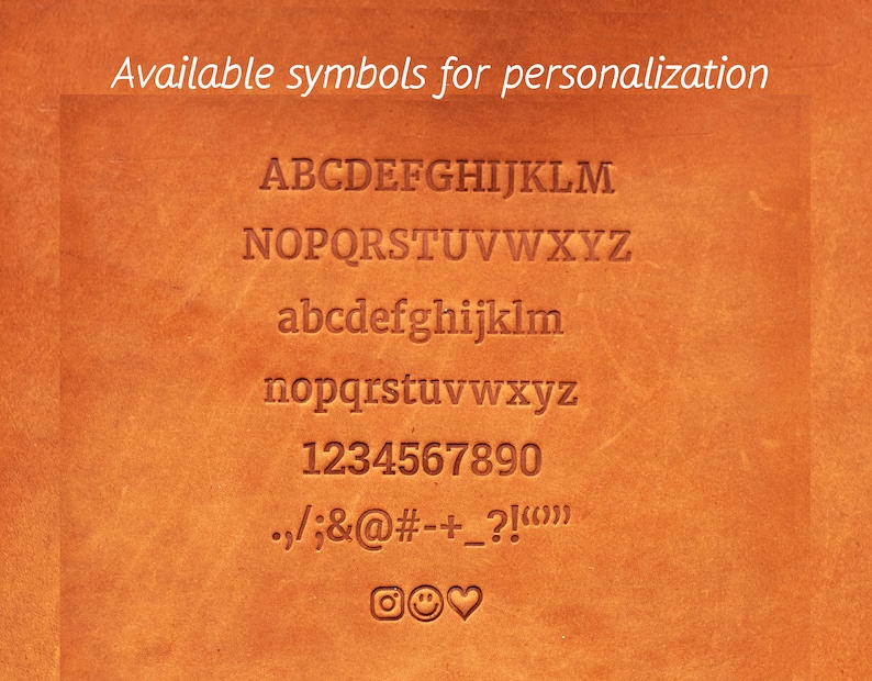 May include: A brown leather surface with a list of available symbols for personalization. The symbols include uppercase and lowercase letters, numbers, punctuation marks, and a few emojis.