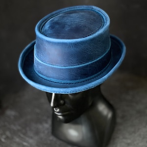 May include: A blue leather fedora hat with a wide brim and a stitched band around the crown.