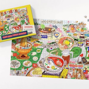 Peut inclure: Un puzzle de 1000 pièces avec une boîte jaune. L'illustration détaillée représente des plats de fondue chinoise et des scènes, avec le texte "Hot Pot Land" et "Hong Kong Puzzle Mystery".