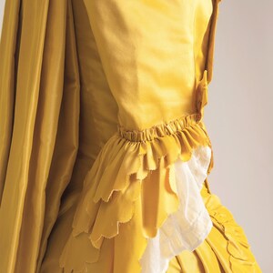 May include: A yellow silk dress with a ruffled sleeve and a flowing skirt.