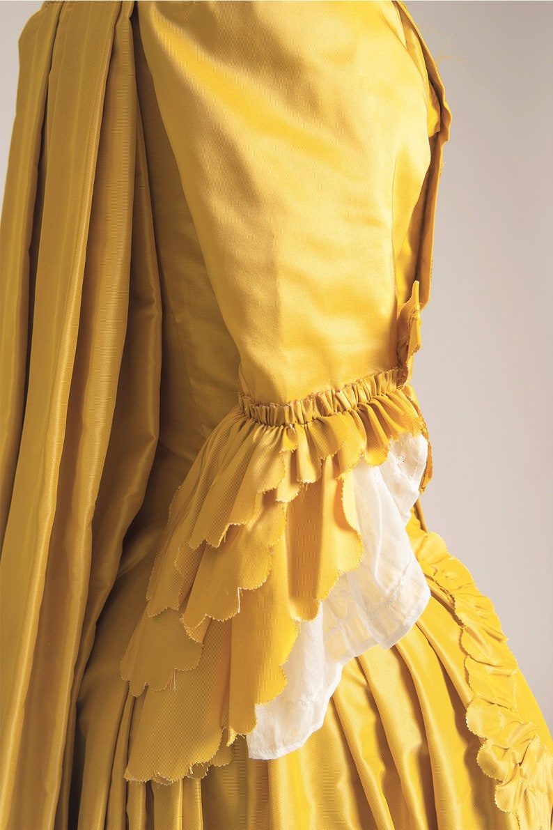 May include: A yellow silk dress with a ruffled sleeve and a flowing skirt.