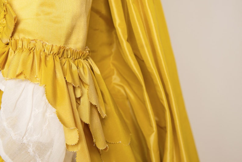 May include: A yellow dress with a ruffled hem and a flowing skirt. The dress is made of a soft, silky fabric.