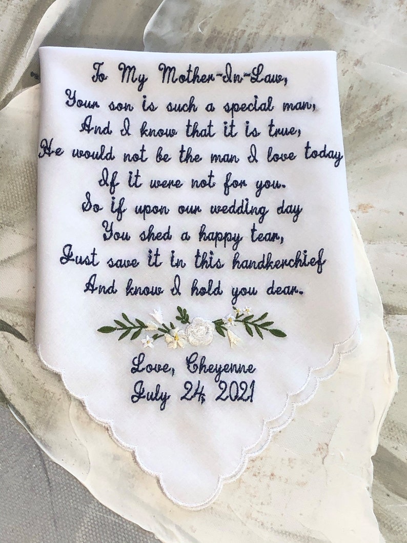 May include: White embroidered handkerchief with a message to a mother-in-law. The message reads: "To My Mother-In-Law, Your son is such a special man, And I know that it is true, He would not be the man I love today If it were not for you. So if upon our wedding day You shed a happy tear, Just save it in this handkerchief And know I hold you dear. Love, Cheyenne July 24, 2021"