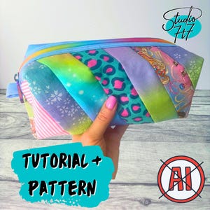 May include: A zipped pouch constructed from diagonal fabric strips featuring a mix of patterns including pink stripes, white cherry blossoms, teal leopard spots, and rainbow gradients. The pouch has a blue zip and a small side loop.