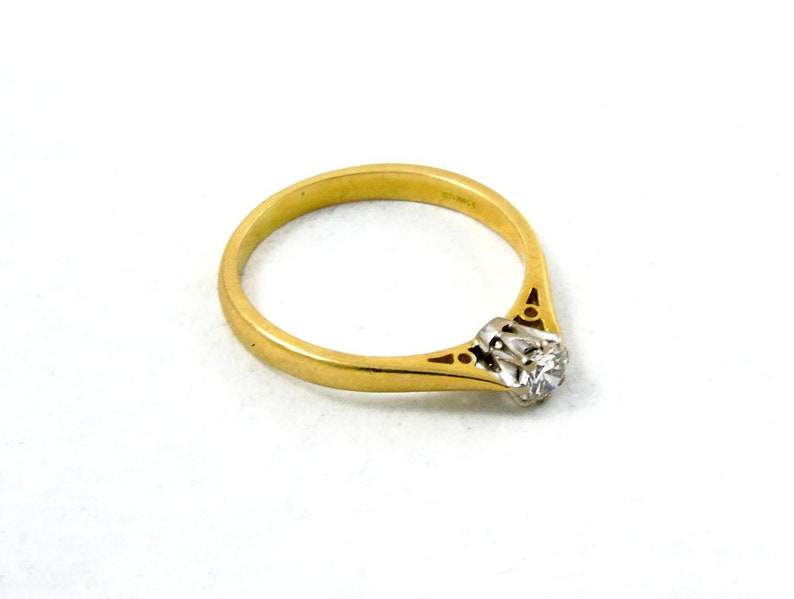 Pu&ograve; includere: Un anello con fascia in oro con un solo diamante incastonato in un design delicato e ornato.