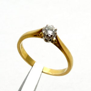 Pu&ograve; includere: Un anello semplice in oro con un solo diamante rotondo incastonato a griffe.