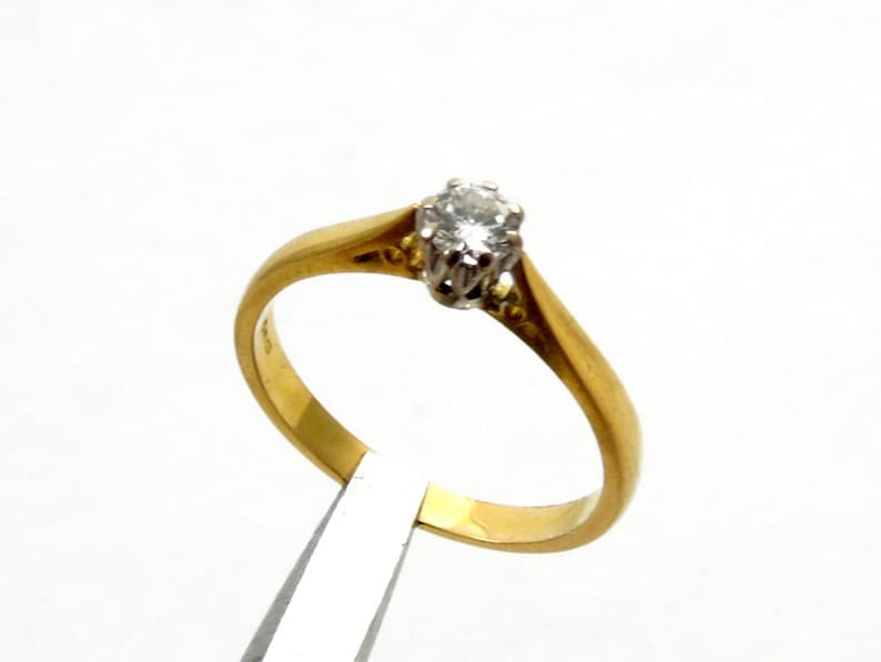 Pu&ograve; includere: Un anello semplice in oro con un solo diamante rotondo incastonato a griffe.