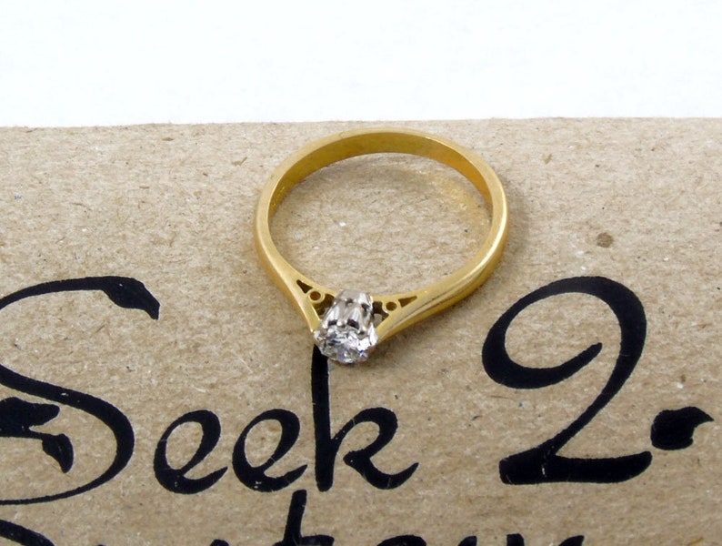 Pu&ograve; includere: Un anello di fidanzamento con fascia in oro con un singolo diamante rotondo incastonato in una delicata montatura a griffe.