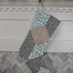 May include: A patchwork Christmas stocking with a blue and white floral pattern, a geometric pattern, and a beige fabric panel.