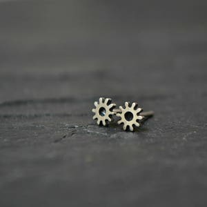 Op de afbeelding: Een paar zilveren oorbellen met een zonnestralenontwerp. De oorbellen zijn klein en delicaat en zouden een geweldig cadeau zijn voor iemand die van de natuur houdt.