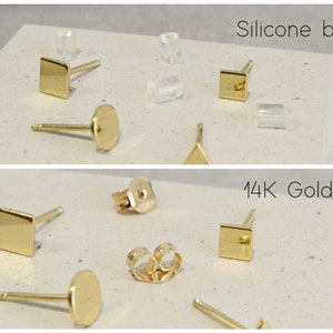 May include: A close-up of earring backs in two styles: silicone and 14K gold. The silicone backs are clear and come in a variety of shapes, including square, round, and triangular. The 14K gold backs are also available in square and round shapes.