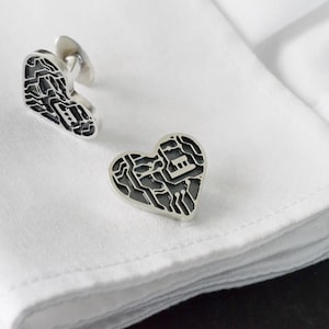 May include: A pair of silver cufflinks in the shape of a heart with a circuit board design.