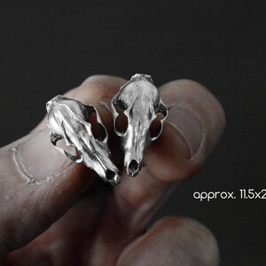 May include: Two silver animal skull earrings, each approximately 11.5x21.5mm in size.