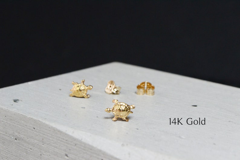 May include: A pair of gold turtle stud earrings. The earrings are made of 14K gold and feature a detailed turtle design. 14K Gold