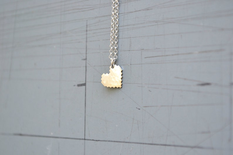 May include: A silver chain necklace with a small, silver, pixelated heart pendant.