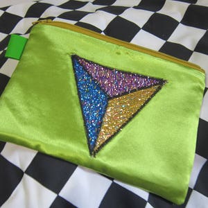 May include: A lime green satin pouch with a black, gold, blue, and purple sequined triangle design.