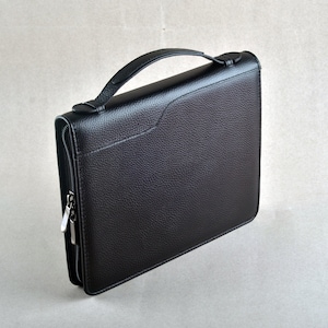 Puede incluir: Un maletín de cuero negro con cierre de cremallera y asa.