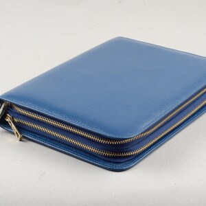 May include: A blue leather zippered portfolio with gold zippers.