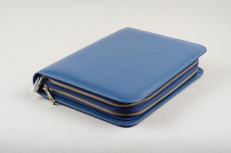 May include: A blue leather zippered portfolio with gold zippers.