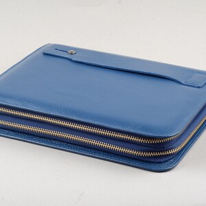 May include: A blue leather zippered clutch with a flap pocket on the front.