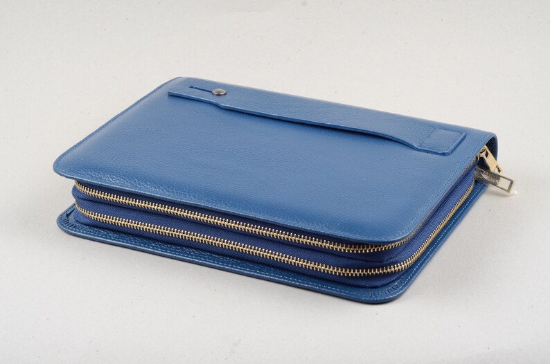 May include: A blue leather zippered clutch with a flap pocket on the front.